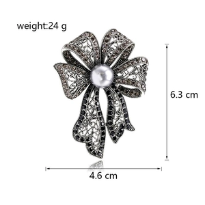 Broche nœud vintage élégante avec strass foncés et perle blanche sur fond blanc