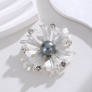 Detail of matte silver flower brooch with large grey pearl and sparkling crystals