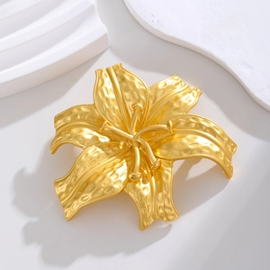 Elegant gold lily flower brooch with hammered texture on white geometric background