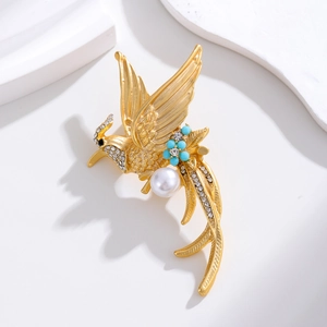 Elegant gold phoenix bird brooch with pearl and blue beads on white stone display