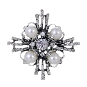 Vintage silver cross brooch with white faux pearls and crystals on a white background