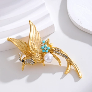 Elegant gold phoenix brooch with a large white pearl and sparkling rhinestones