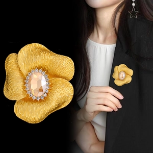 Elegante spilla a fiore dorata con gemma color champagne e cristalli scintillanti