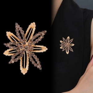 Golden sunflower brooch with smoke grey crystals shown on black fabric background