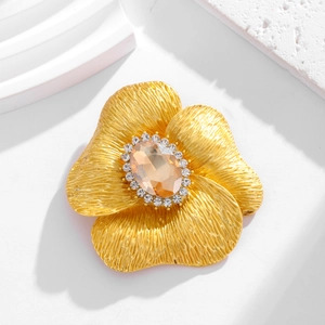 Spilla vintage a fiore dorata con ambra e zirconi su sfondo bianco geometrico