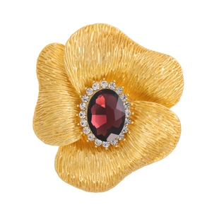 Dettaglio di spilla vintage a fiore dorata con rubino rosso centrale e cristalli