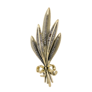 Macro view of gold wheat ear brooch featuring crystal pavé details and bow accent