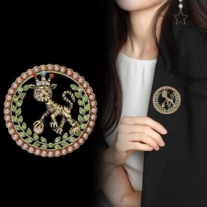 Broche lion dorée avec perles et strass verts au design élégant et couronne royale