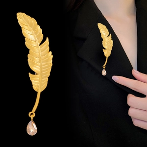 Golden feather brooch with pink crystal drop pendant on black suit lapel