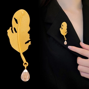 Goldene Vintage Federbrosche mit Wassertropfenanhänger an einem schwarzen Blazer