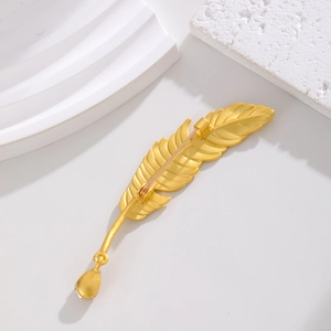 Golden alloy feather brooch with water drop pendant on minimalist stone display