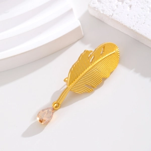 Eleganter goldener Feder-Blatt-Anstecker mit Champagner-Tropfen auf weißem Hintergrund