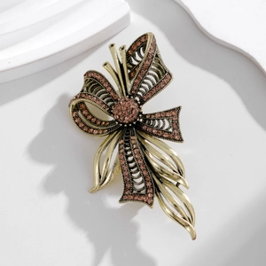 Vintage style bow brooch in bronze metal with amber crystals on white geometric background
