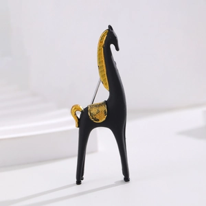 Détail d'une broche cheval noir mat et or givré sur un support d'exposition blanc