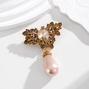 Macro shot of vintage gold flower brooch with leaf details and water drop pink pearl