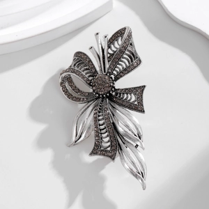 Detailed macro of vintage silver bow brooch with grey rhinestones on a white step