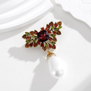 Macro shot of vintage gold floral brooch with red rhinestones and teardrop pearl pendant