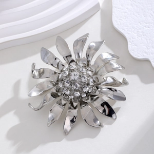 Broche tournesol argentée avec cristaux étincelants sur fond blanc minimaliste ondulé