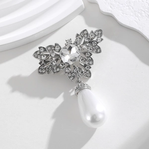 Detailed view of a silver butterfly brooch with crystals and a white pearl drop