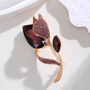 Macro shot of tulip brooch with purple crystals and gold stem on textured surface