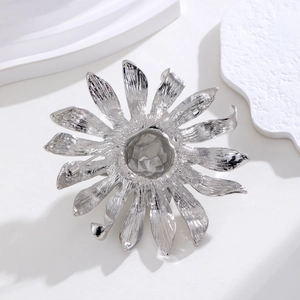 Détail d'une broche tournesol argentée montrant les pétales texturés et le fermoir