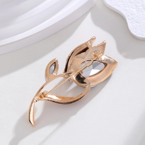Elegant gold tulip brooch with a large faceted clear crystal on a white stone surface