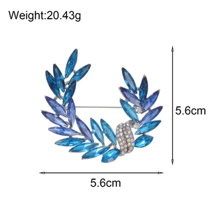 Elegant crystal wheat brooch with blue marquise stones and diamond accents on white backdrop