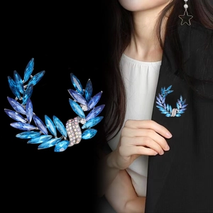Elegant crystal leaf brooch with blue and purple gems shown on a model and black background