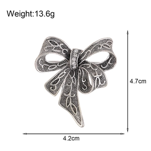 Vintage silver bow brooch with white rhinestones and detailed hollow engraving