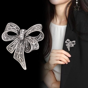 Detailed close-up and model shot of a vintage silver bow brooch with white rhinestones