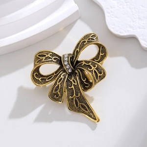 Vintage gold alloy bow brooch with black hollow patterns and clear rhinestones