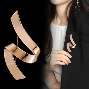 Detail view of rose gold ribbon brooch with mirror polish and pin back on black background