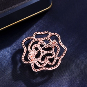 Broche fleur évidée en or rose avec zircons scintillants sur fond de soie bleu foncé