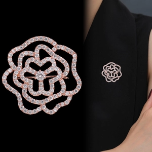 Macro de la broche camélia en or rose sertie de zircons sur le revers d'un blazer noir