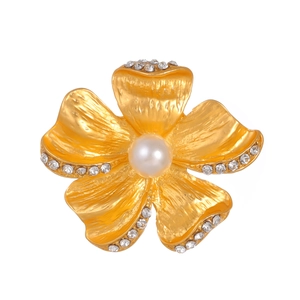 Detail of a vintage flower brooch with metallic texture, rhinestones, and center pearl