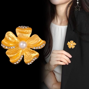Vintage gold flower brooch with pearls and crystals shown on suit and black backdrop