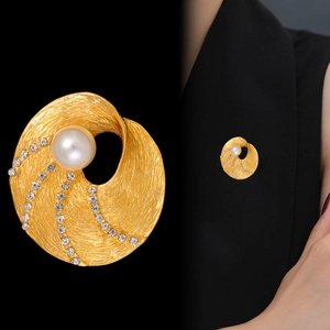 Spilla vintage dorata con design a spirale, perla bianca centrale e dettagli in zirconi