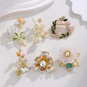 Détail de six broches florales élégantes avec perles et cristaux sur support blanc
