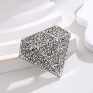Vintage silver alloy diamond-shaped brooch with sparkling rhinestones on white geometric stand