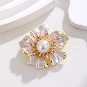 Broche fleur en émail rose avec perle centrale et cristaux sur fond blanc épuré