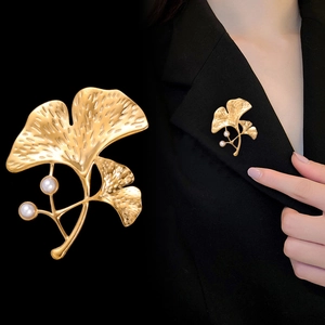 Détail macro de broche feuille de ginkgo dorée avec perles et mannequin en blazer