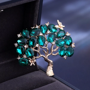 Elegante spilla ad albero con cristalli verdi e farfalla in una scatola per gioielli