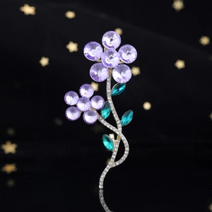 Détail d'une broche fleurie avec cristaux violets et feuilles vertes serties