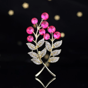 Détail de la broche fleur dorée avec cristaux roses et feuilles serties de strass