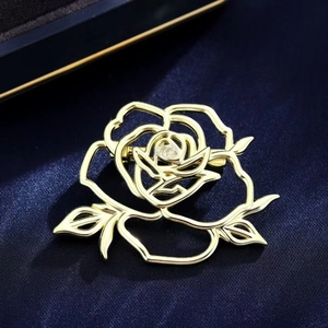 Elegant gold hollow rose brooch with leaf accents on luxury blue silk background