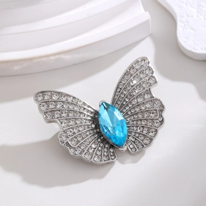 Makro-Detail der Schmetterlingsbrosche mit blauem Marquise-Stein und Kristall-Pavé