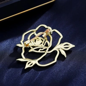 Back view of hollow gold rose brooch with safety pin on elegant dark blue satin