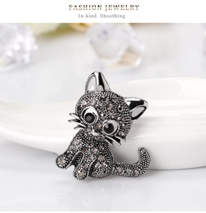 Detailed close-up of a silver cat brooch with grey rhinestones and black gem eyes