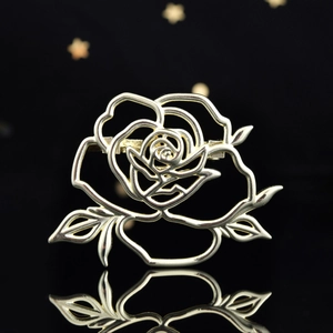 Elegant hollow gold rose flower brooch with intricate metal cutout design on black background