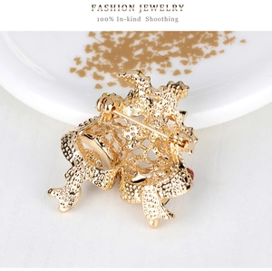 Golden Christmas bell brooch featuring intricate textured metal and horizontal pin clasp